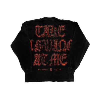 A black Kublai Khan Alstyle long-sleeve t-shirt features bold red Gothic text on the back: “TAKE A SWING AT ME.” Smaller white text at the bottom reads “Re-ment x H.O.A.”—perfect for fans of unique custom apparel.