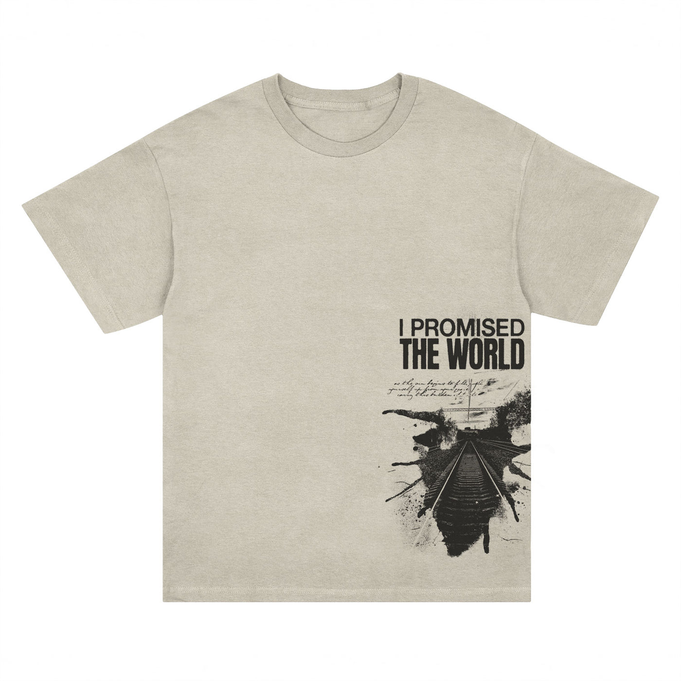 The I Promised The World beige comfort wash t-shirt features black "I PROMISED THE WORLD" text, train tracks with abstract ink splatter, and handwritten script accents. Now available for presale; ships 1/9/26.