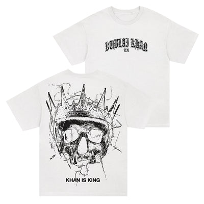 White Comfort Colors t-shirt by Kublai Khan TX with bold black textured logo on front. Back showcases a large cracked skull with spiked crown and “KHAN IS KING” text. Exclusive presale—grab this premium printed garment now!.