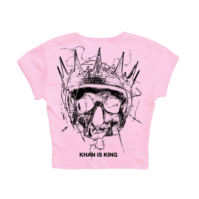 Light pink Kublai Khan TX 1010 cropped t-shirt with a black crowned skull and “KHAN IS KING” text. Available for presale now; shipping begins 10/17/25.