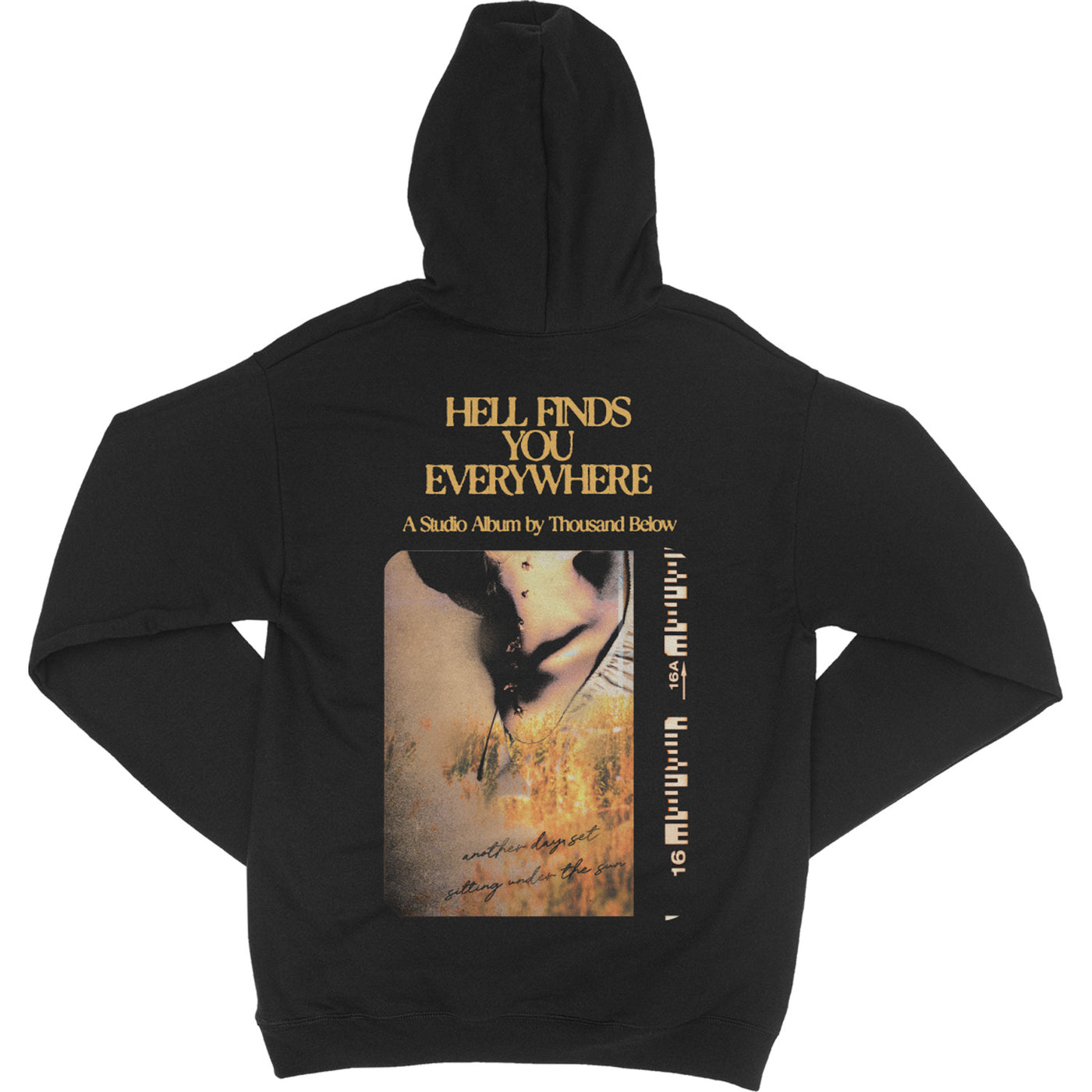 back of black pullover hoodie with yellow text "hell finds you everywhere a studio album by thousand below" at the top with an image of burned camera film underneath 